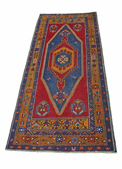A vintage handmade Turkish Taspinar runner rug featuring a central diamond motif on a red field.