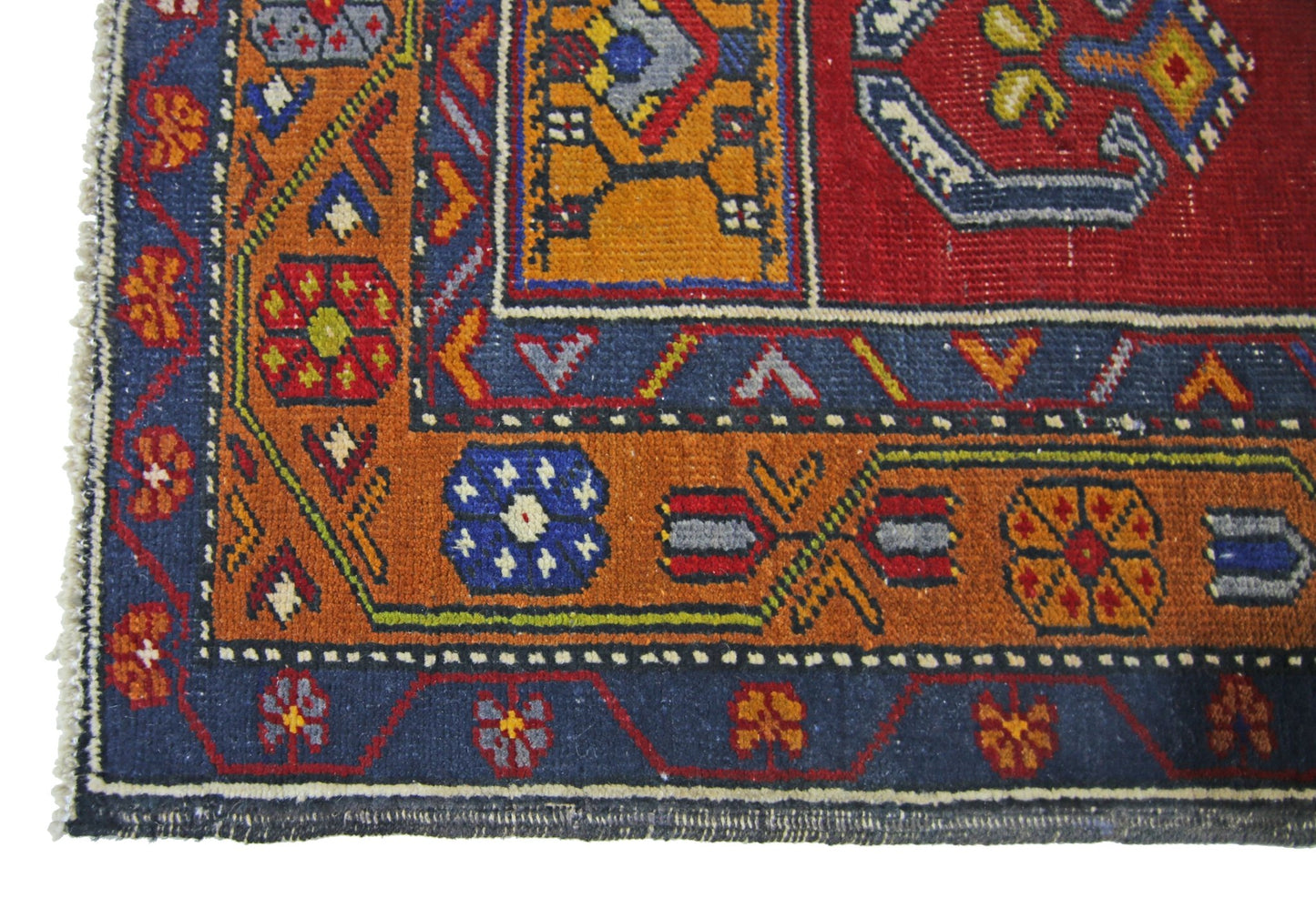 A vintage Turkish Taspinar rug featuring geometric patterns in red, blue, and orange wool.