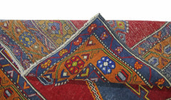A folded vintage Turkish Taspinar rug featuring intricate geometric patterns in red, blue, and orange.