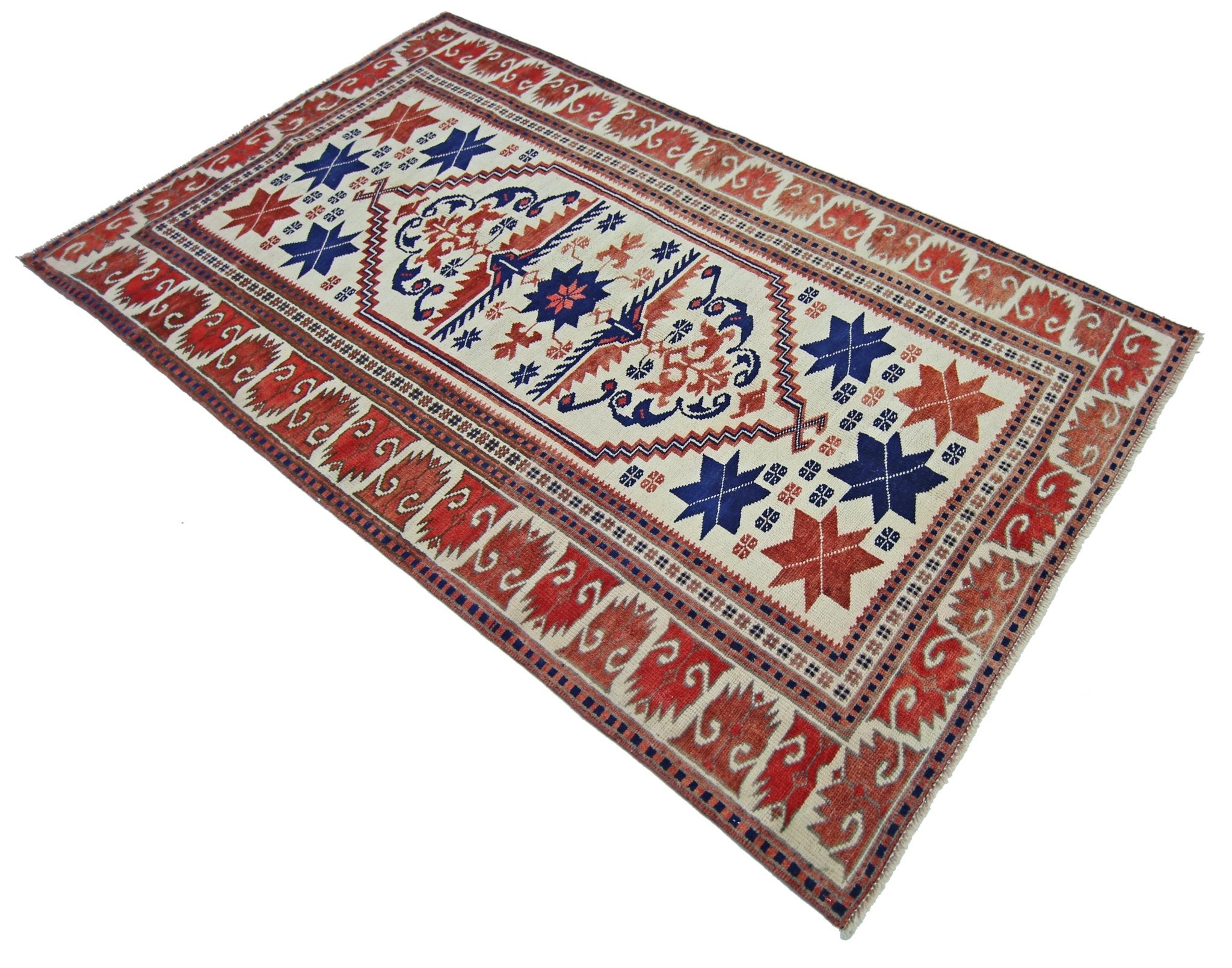 A vintage handmade Turkish rug featuring geometric star motifs in red and blue on a cream field.