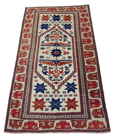 A vintage handmade Turkish wool rug featuring a geometric star pattern in red, blue, and cream.