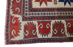 A vintage handmade Turkish rug featuring a geometric pattern in red, blue, and cream wool.