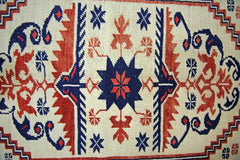 A vintage handmade Turkish rug featuring a central blue star motif with red floral accents on a cream background.