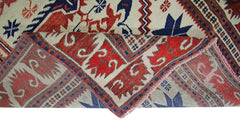 A vintage handmade Turkish wool rug featuring a geometric pattern in red, blue, and cream.