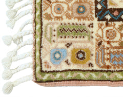 A close-up of a vintage Turkish Yoruk rug featuring geometric patterns in muted tones and a tasseled edge.