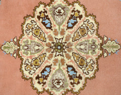 A vintage Turkish Yoruk rug featuring a central floral medallion on a soft pink background.