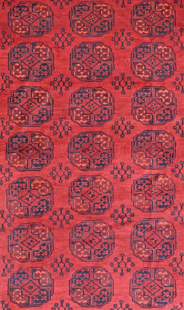 A vintage Afghan Turkmen rug featuring a repeating geometric pattern in deep red and dark blue.