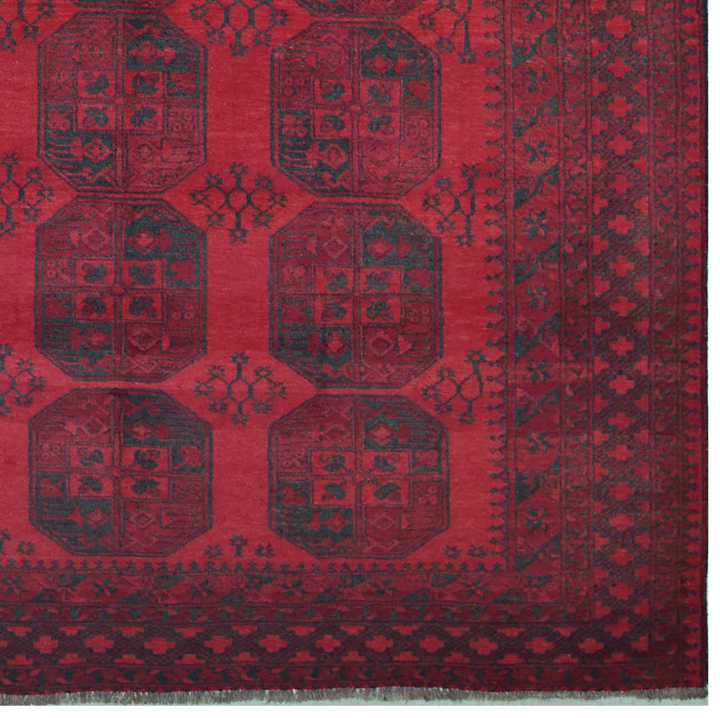 A vintage handmade Afghan Turkmen rug featuring dark geometric octagonal motifs on a red field.