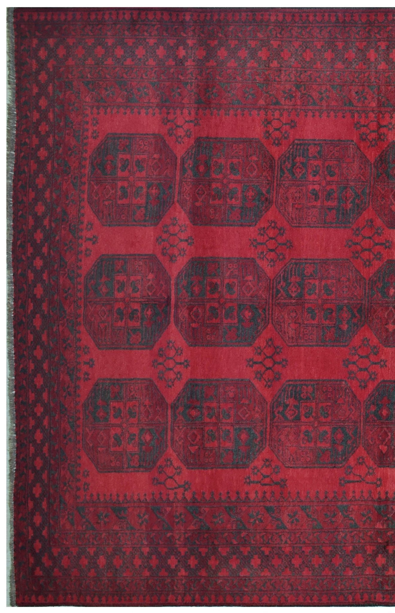 A vintage handmade Afghan Turkmen rug featuring dark geometric octagons on a deep red background.