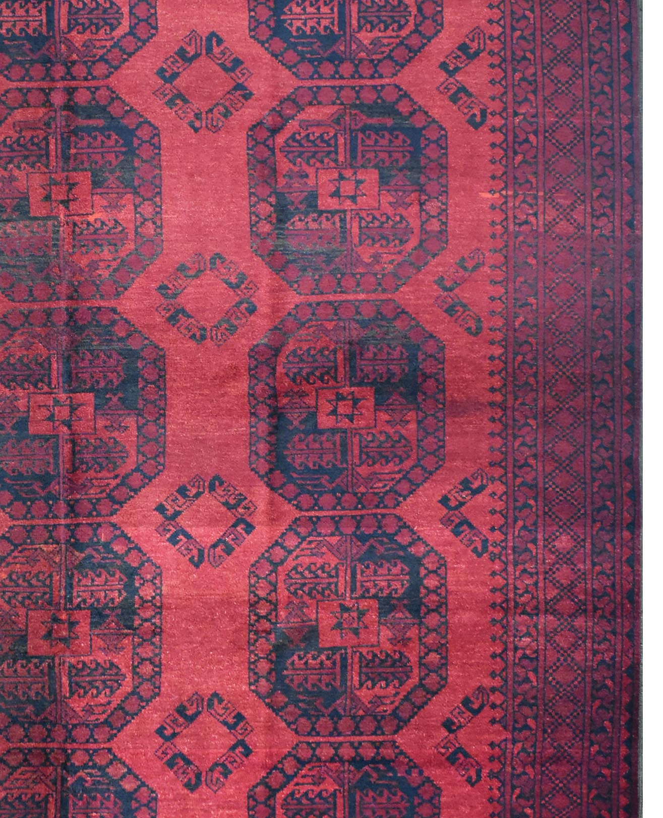 A vintage handmade Afghan Turkmen rug featuring repeating dark blue geometric guls on a red field.