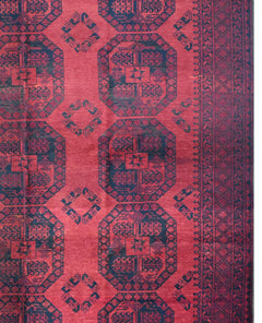 A vintage handmade Afghan Turkmen rug featuring repeating dark blue geometric guls on a red field.