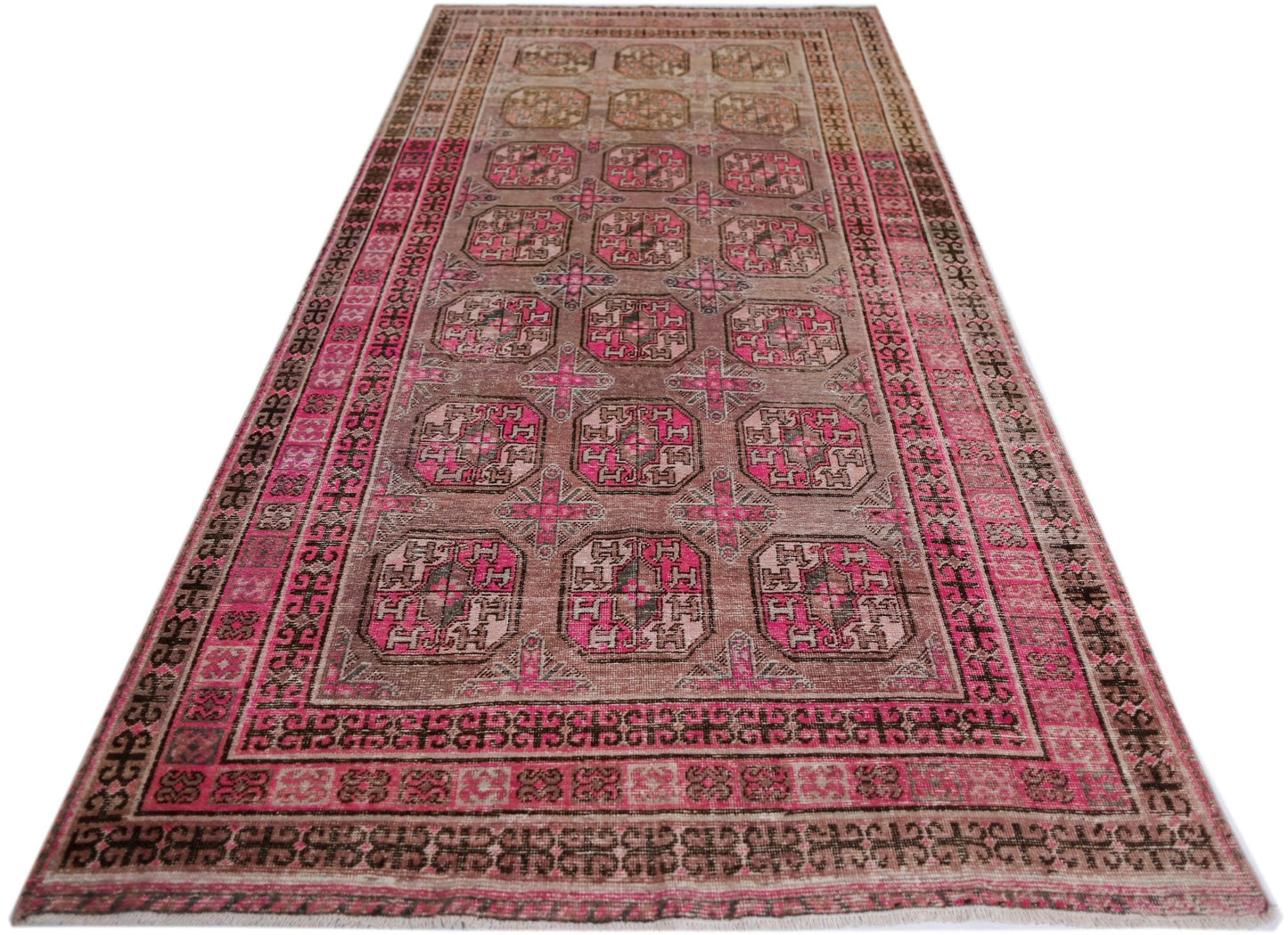 An antique handwoven Afghan Turkmen rug featuring a repeating pomegranate pattern in vibrant pink.