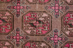 An antique handwoven Khotan rug featuring a geometric pomegranate pattern in vibrant pink tones.