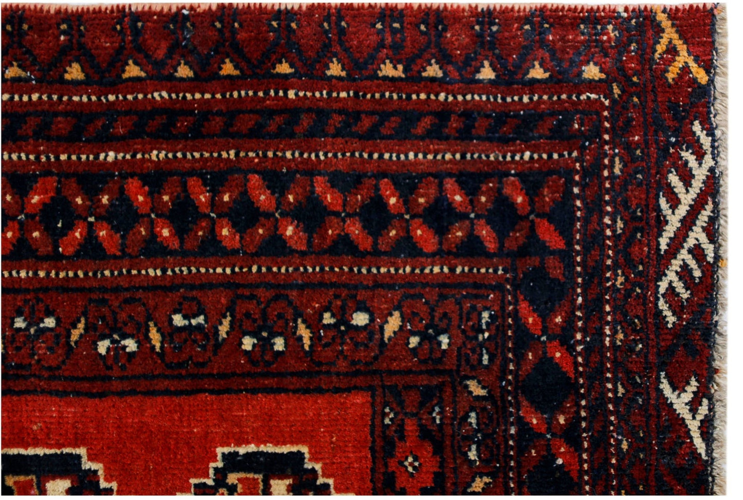A close-up of a vintage Afghan Baluch rug featuring traditional geometric patterns in red and black.