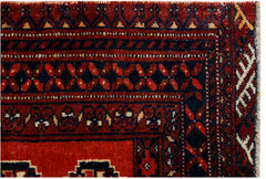 A close-up of a vintage Afghan Baluch rug featuring traditional geometric patterns in red and black.