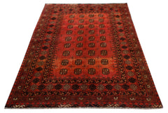 A vintage handwoven Afghan Turkmen rug featuring a repeating geometric pattern on a red field.
