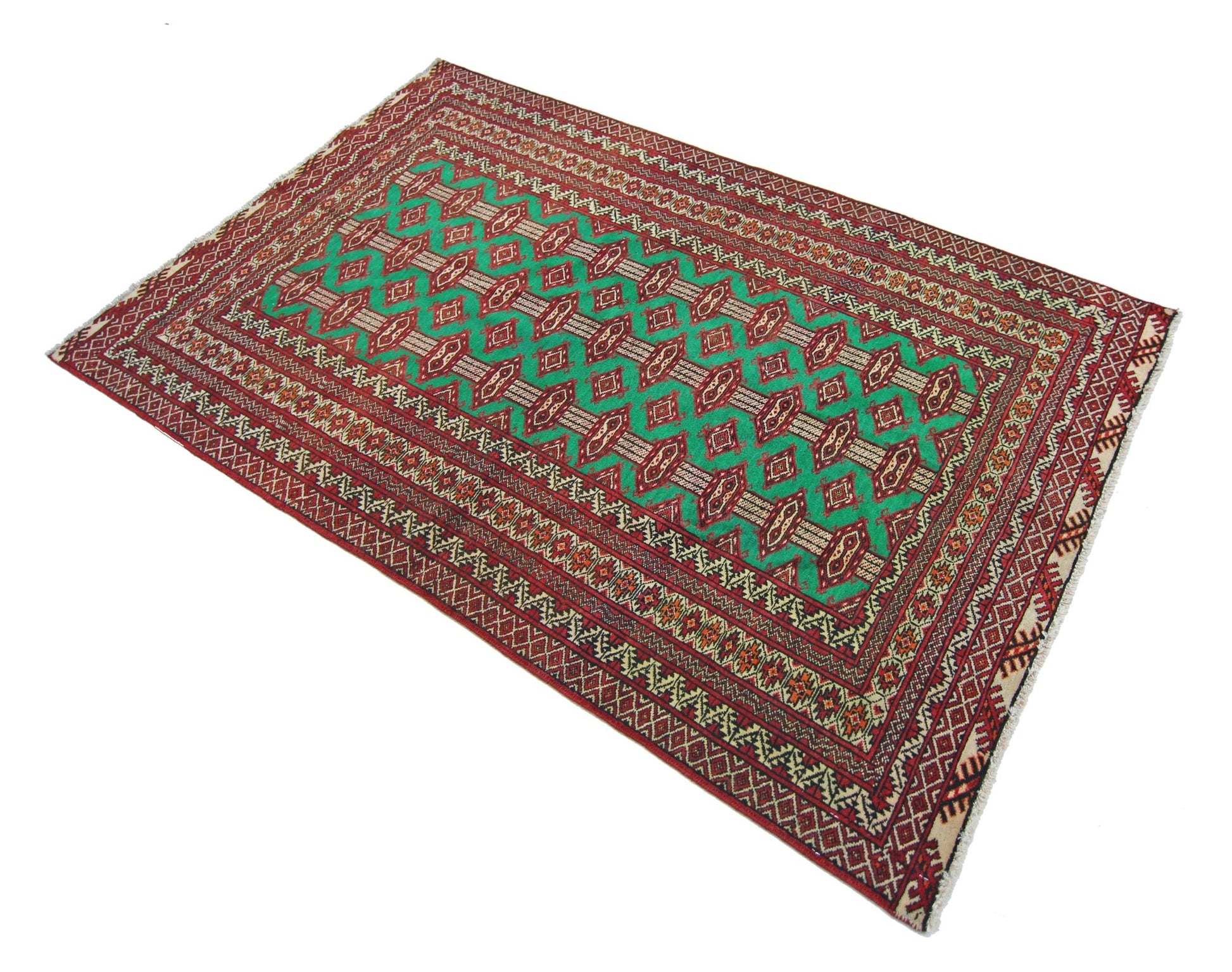 A vintage Persian Turkmen rug featuring a repeating geometric pattern in green, red, and cream.