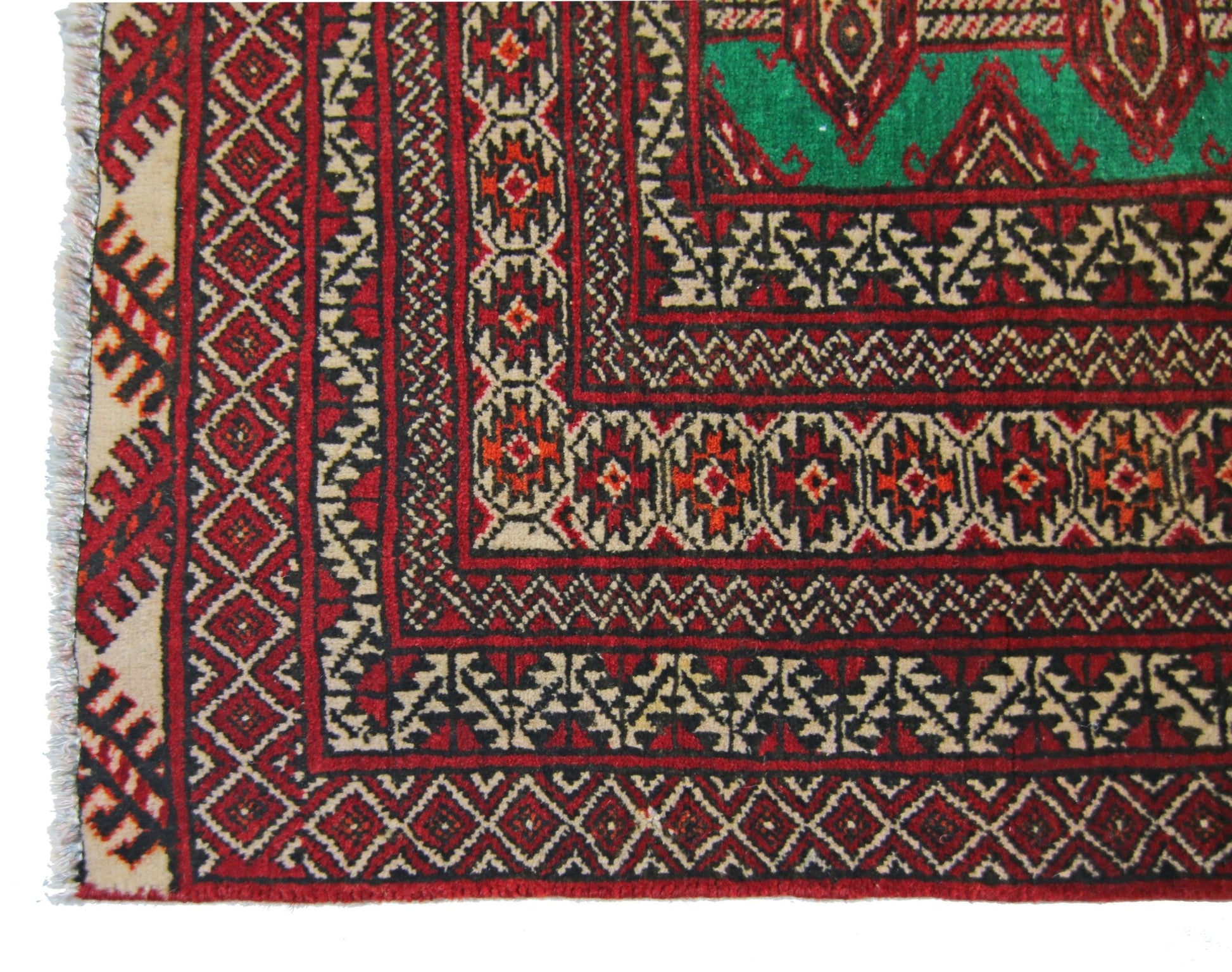 A vintage Persian Turkmen rug featuring intricate geometric patterns in red, black, and green.