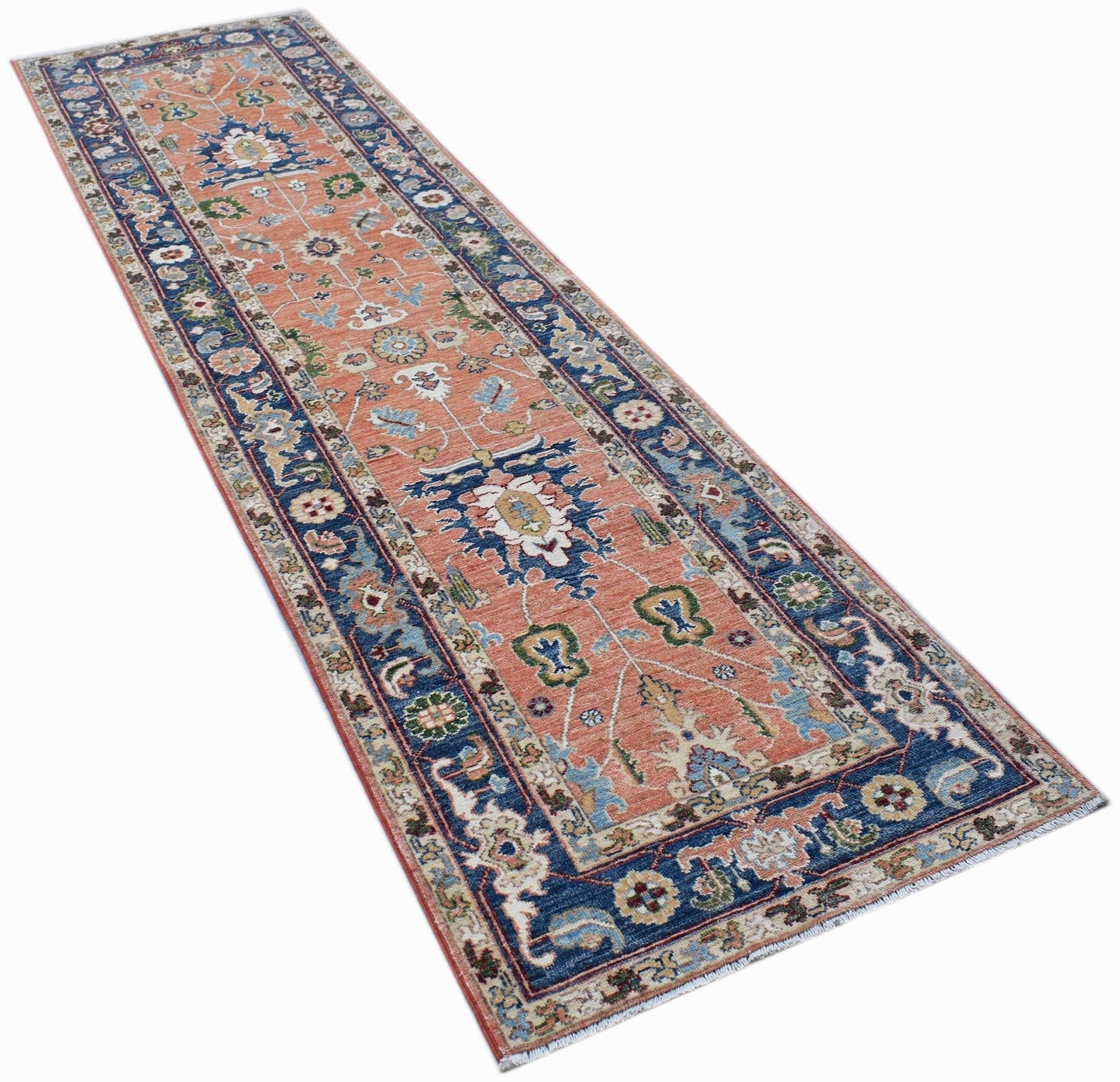 A handmade Afghan Chobi runner rug featuring a traditional floral pattern in peach and blue tones.