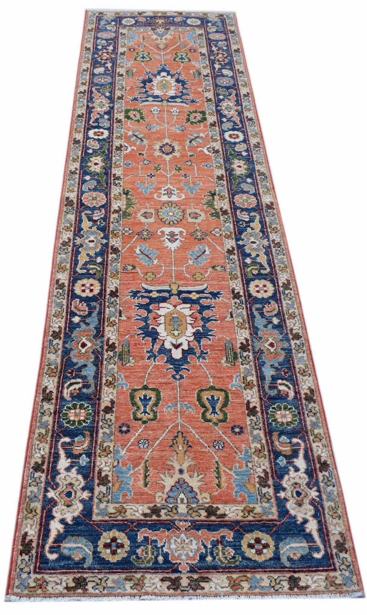 A handmade Afghan Chobi runner rug featuring a traditional floral pattern in orange and blue.