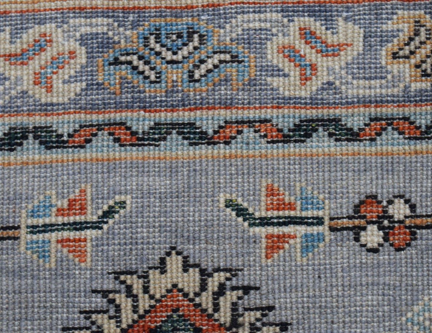 A close-up of a hand-knotted Afghan Chobi runner featuring intricate floral patterns in wool.