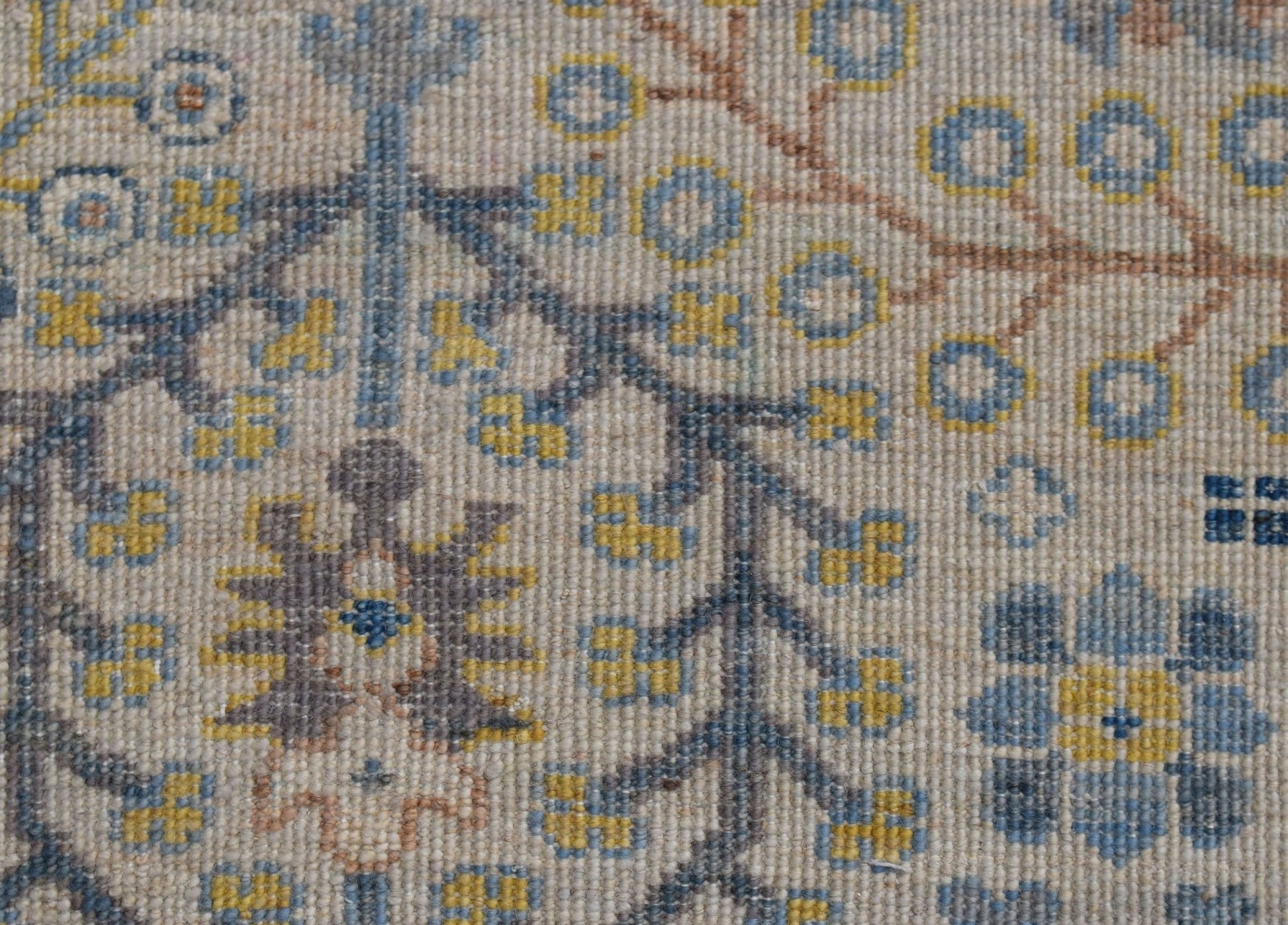 A close-up of an Afghan Chobi runner featuring intricate floral patterns in blue and yellow wool.