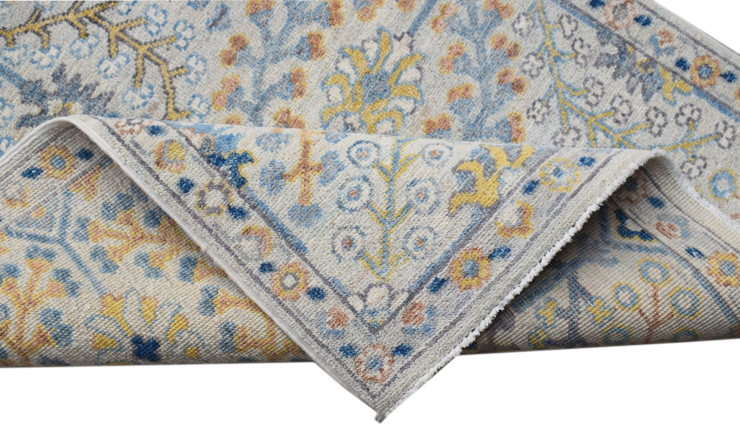 A hand-knotted Afghan Chobi runner featuring a traditional floral pattern in blue, yellow, and tan.