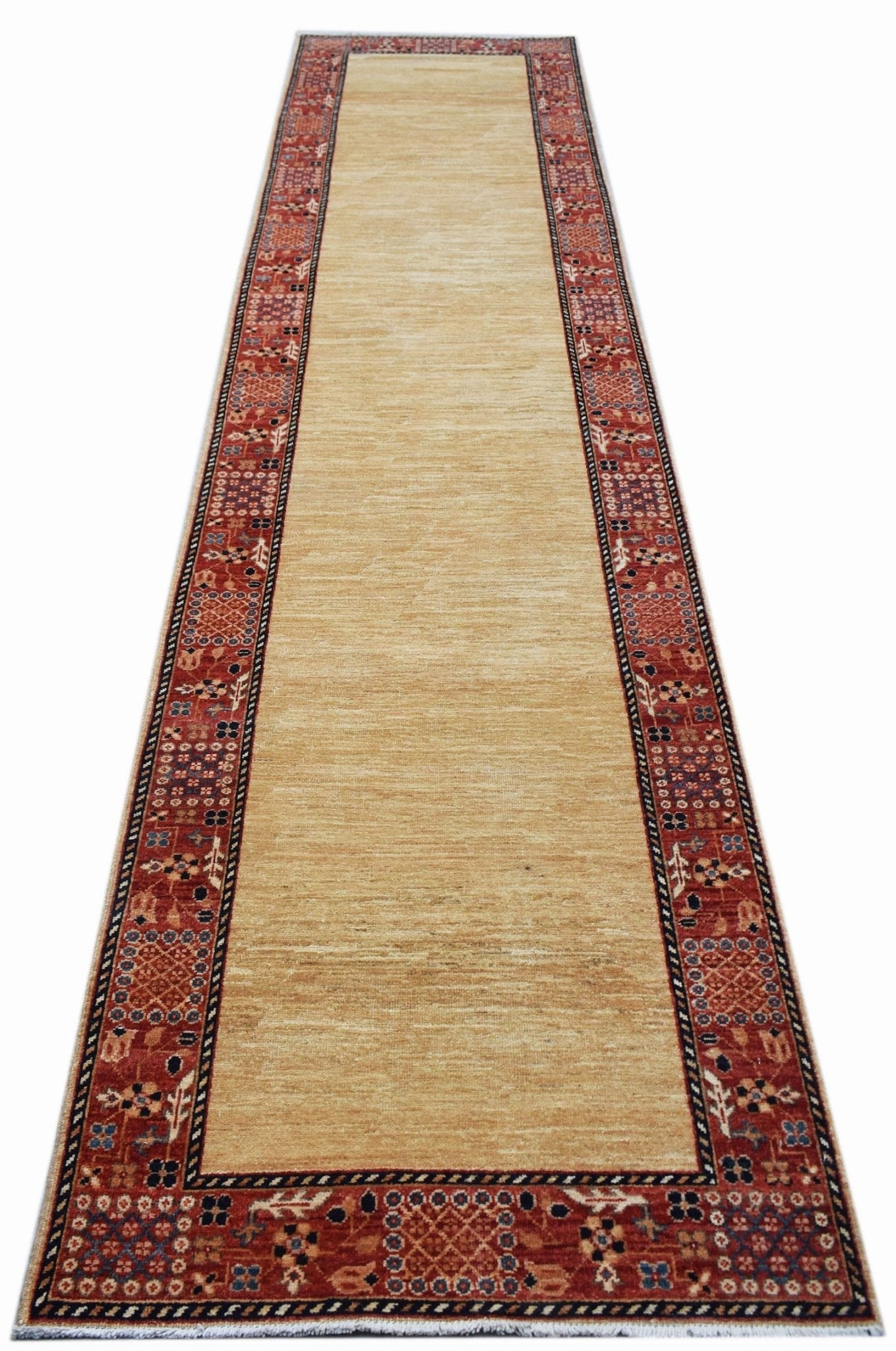 An Afghan Chobi runner rug featuring a solid tan field framed by a decorative red patterned border.