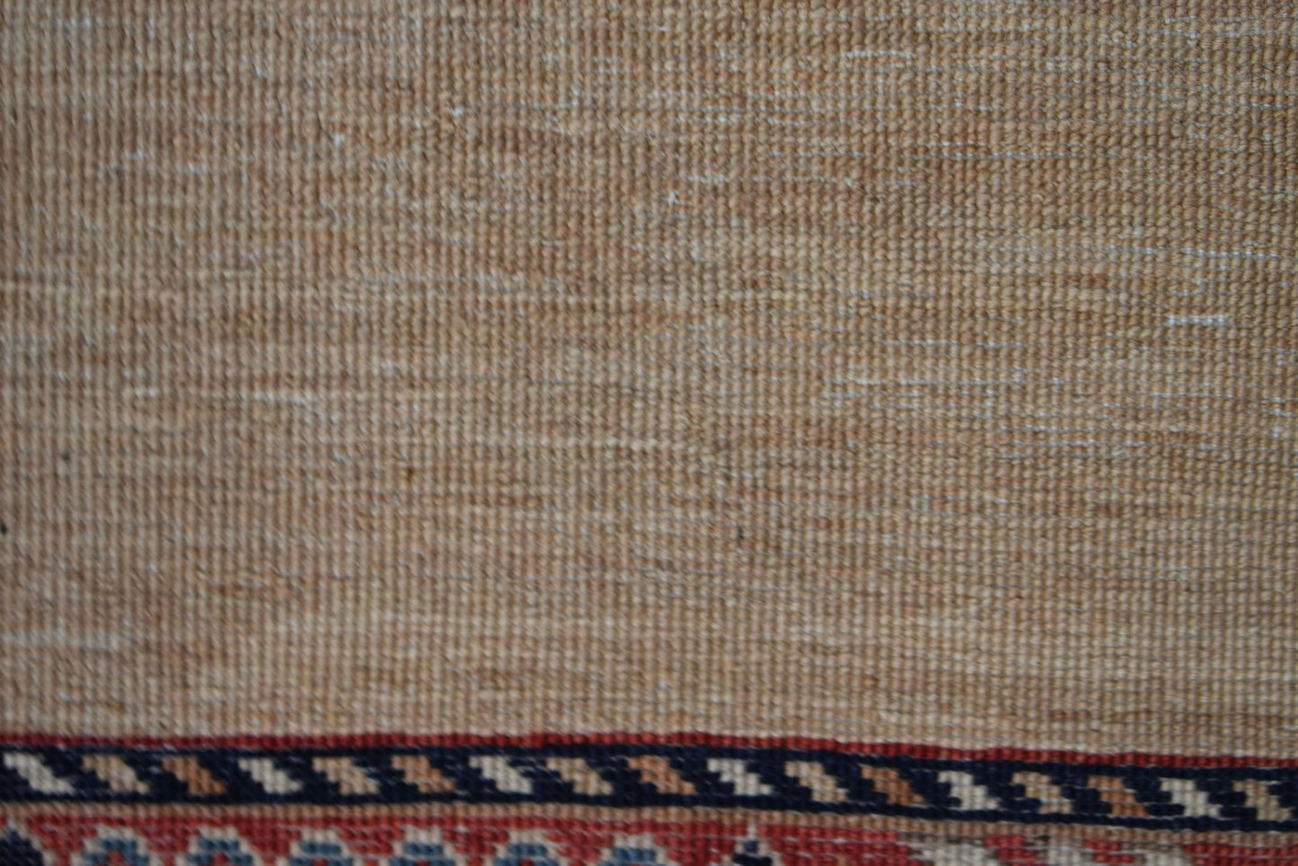 A close-up of a handwoven Afghan Chobi runner featuring a textured beige field and a patterned border.