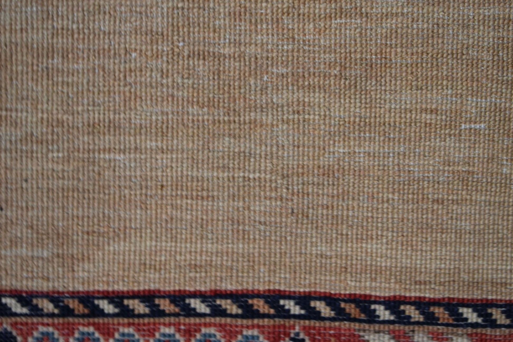A close-up of a handwoven Afghan Chobi runner featuring a textured beige field and a patterned border.