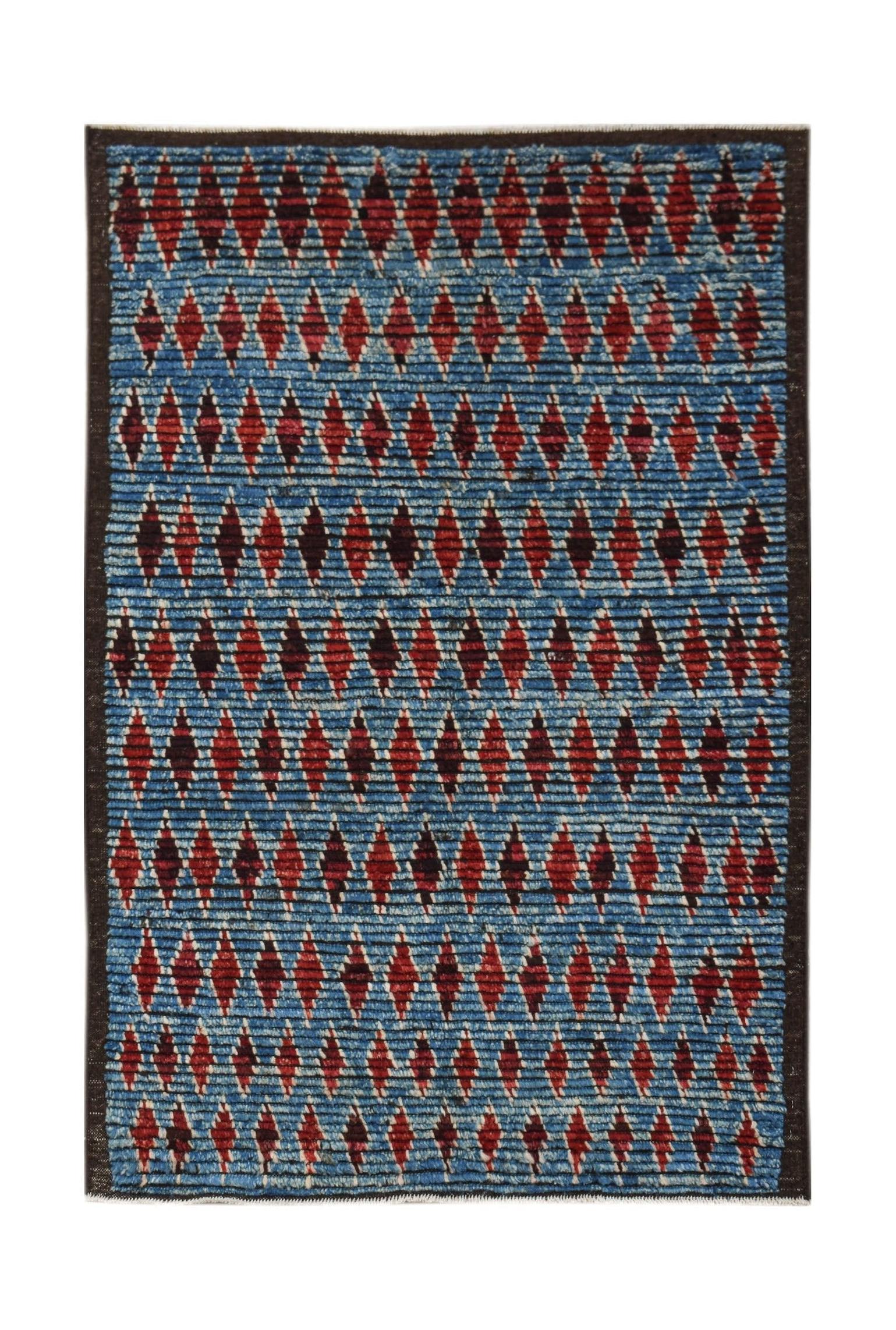 Hand-knotted Afghan rug featuring a blue background with rows of red geometric diamond patterns.