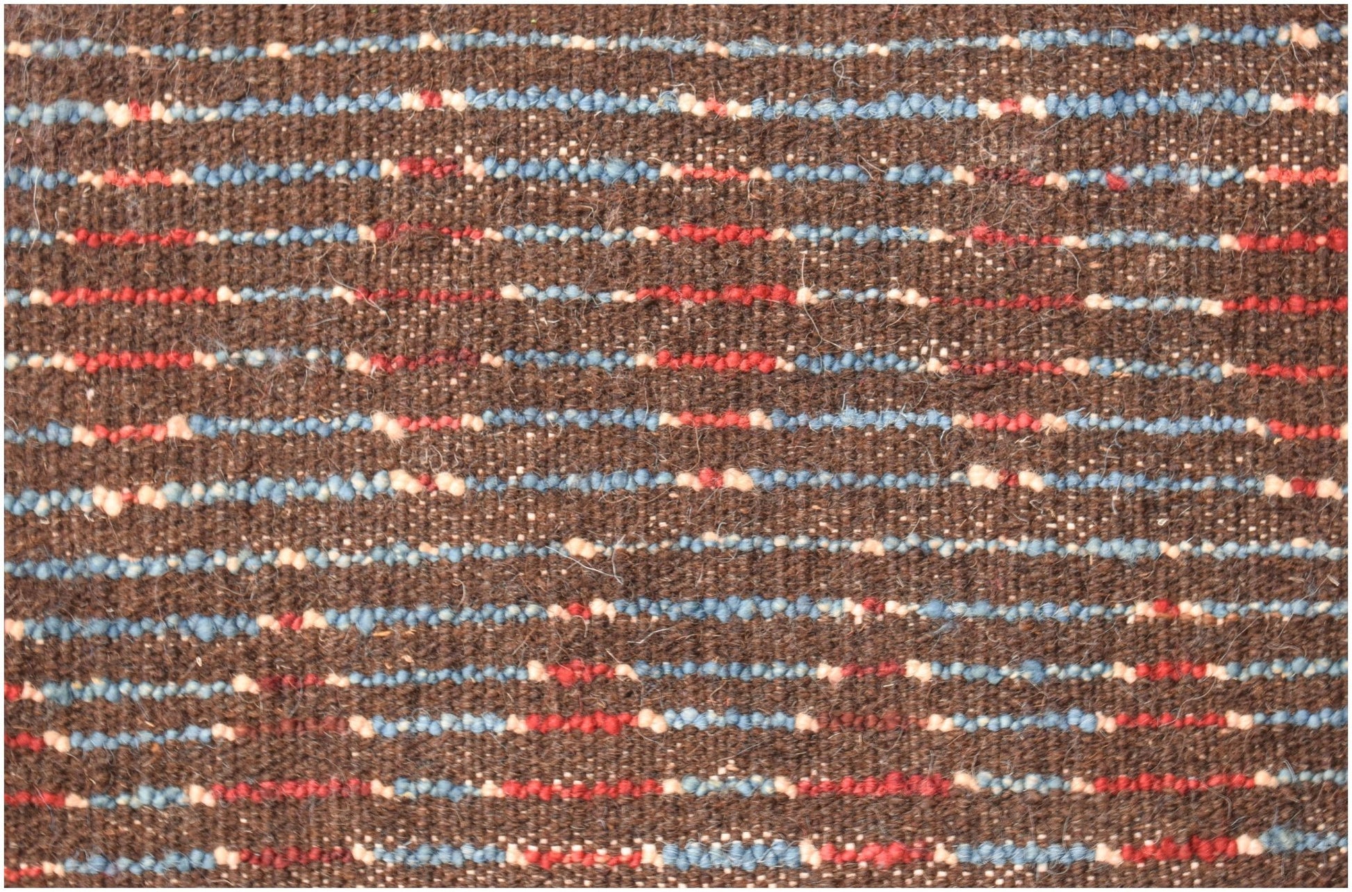 A brown hand-knotted wool rug featuring horizontal stripes of blue, red, and cream accents.