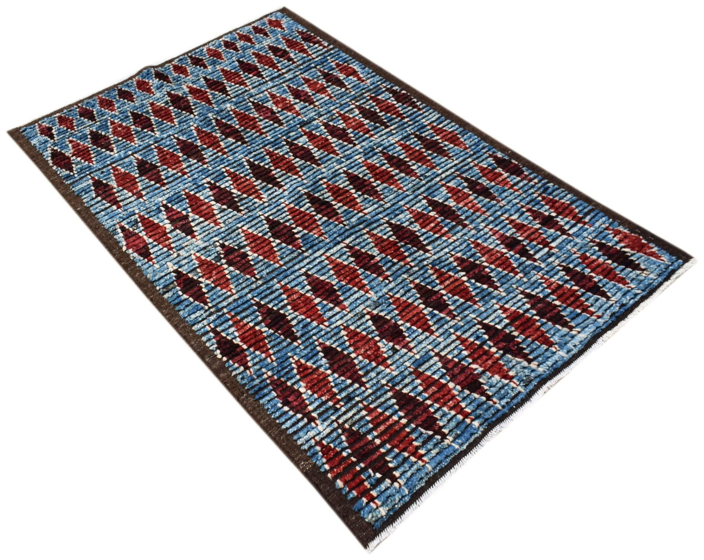An Afghan Yekta rug featuring a blue background with repeating red and dark geometric diamond motifs.