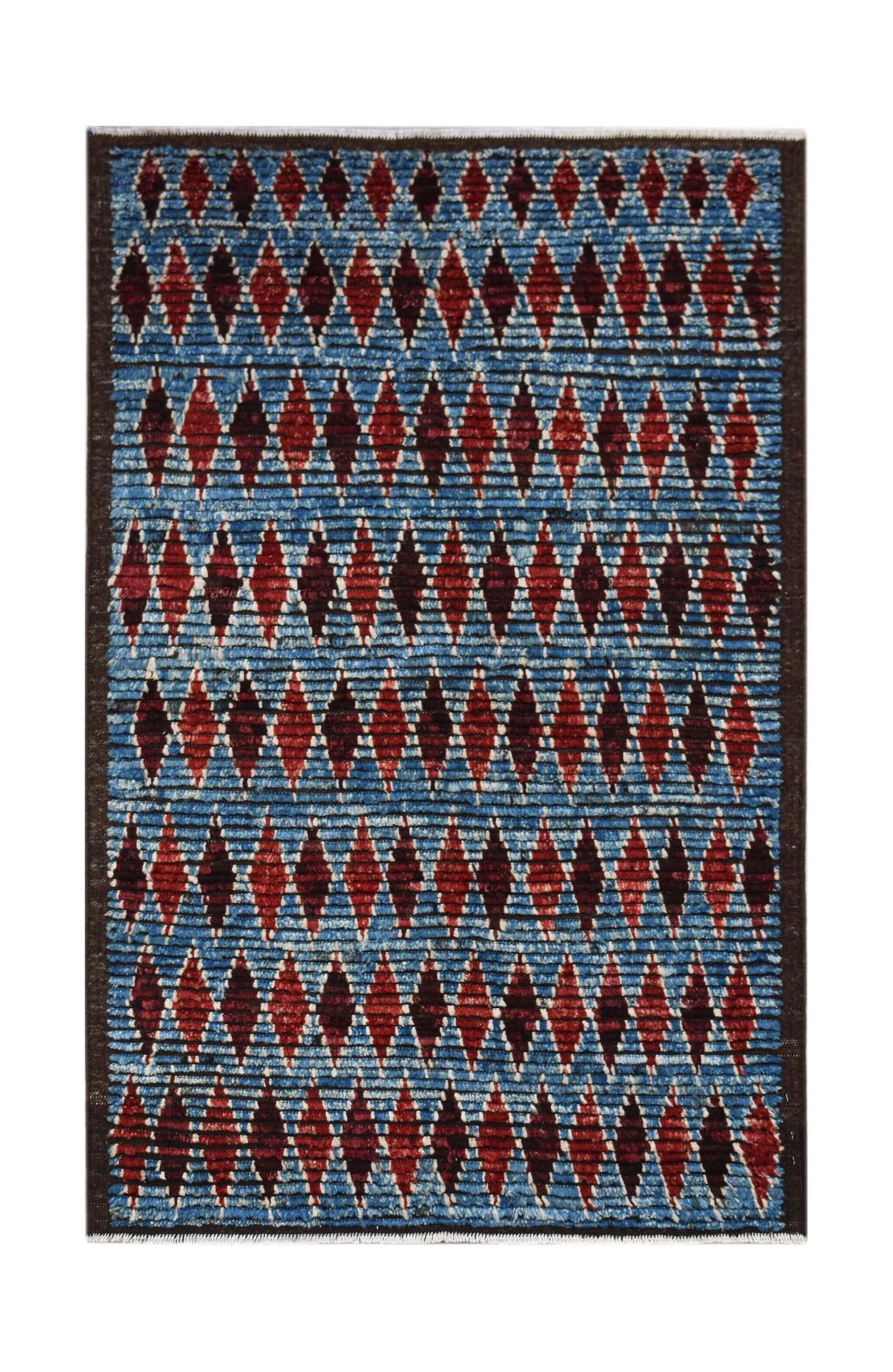 Hand-knotted Afghan rug featuring a blue background with repeating red diamond patterns.