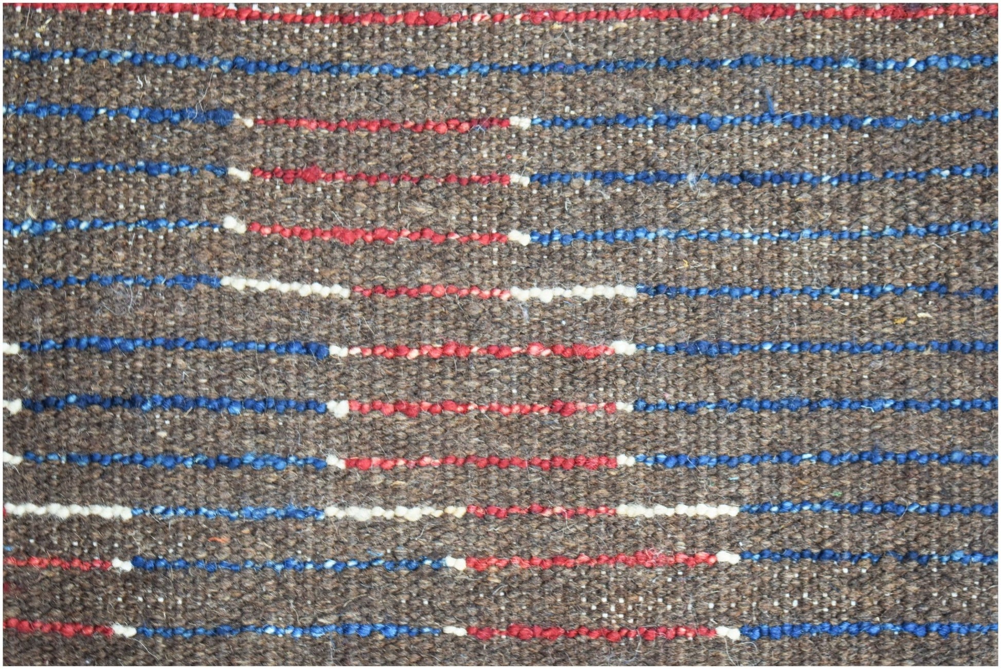 A hand-knotted Afghan rug featuring a brown wool base with horizontal red, blue, and white stripes.