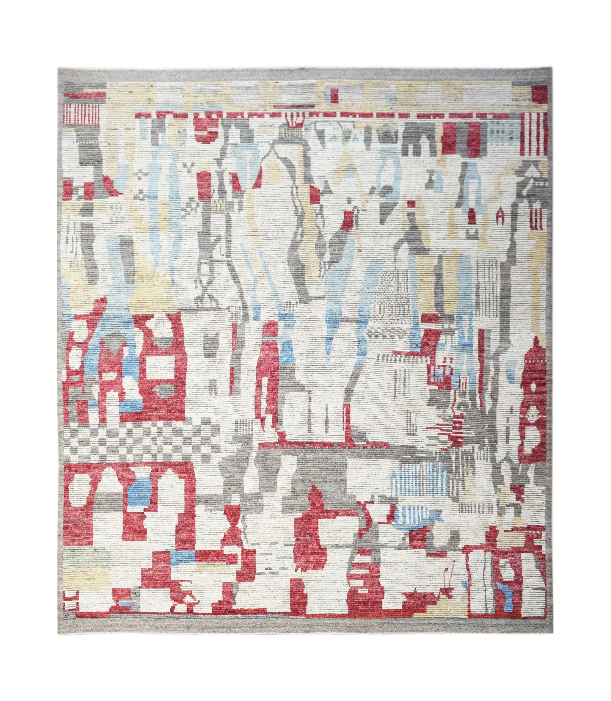 A hand-knotted wool rug featuring an abstract geometric pattern in red, blue, grey, and cream.