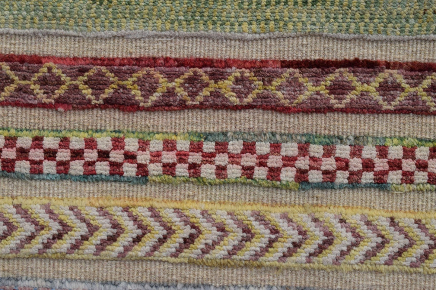 A close-up of an Afghan Yekta runner featuring horizontal bands of geometric and checkered patterns.