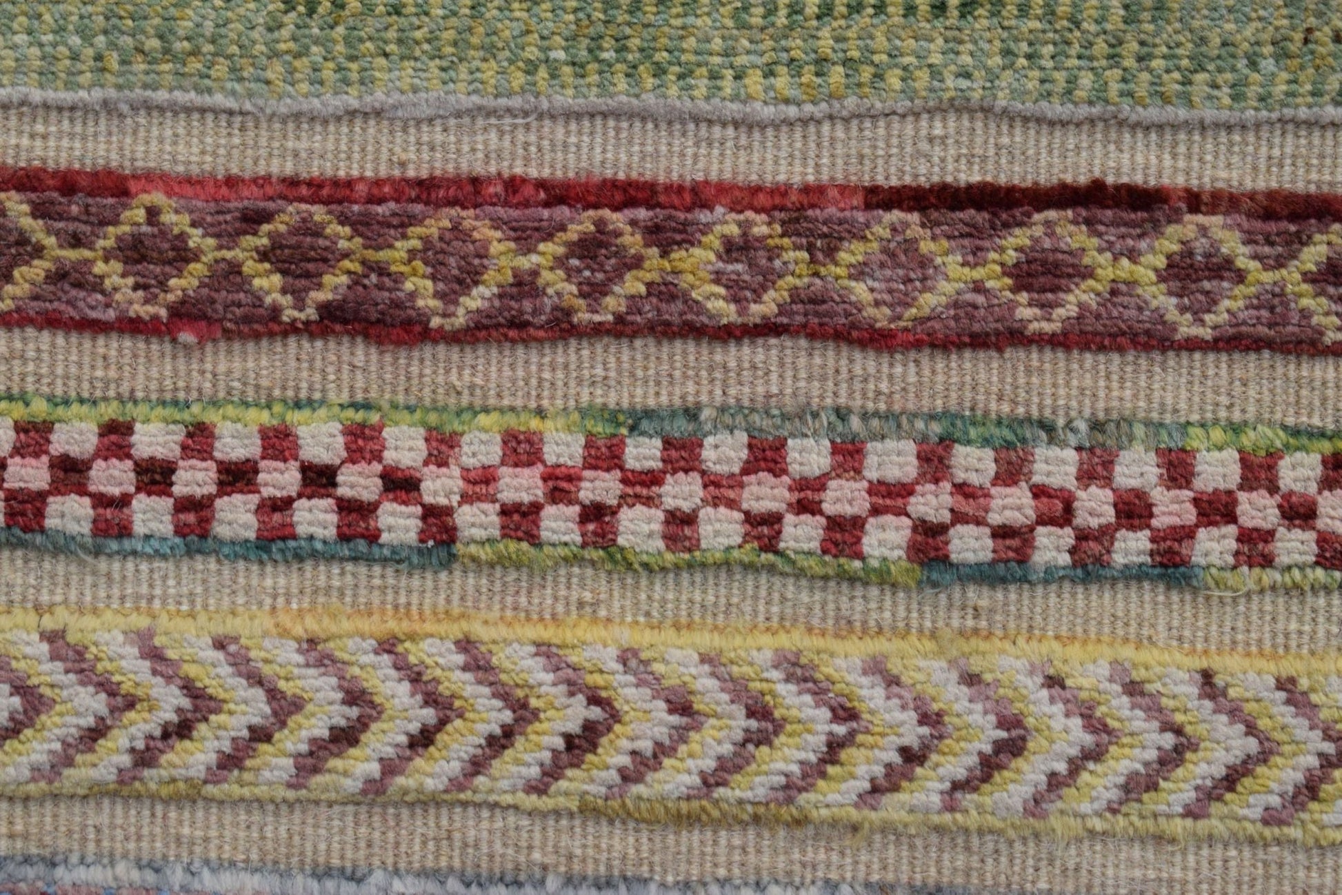 A close-up of an Afghan Yekta runner featuring horizontal bands of geometric and checkered patterns.