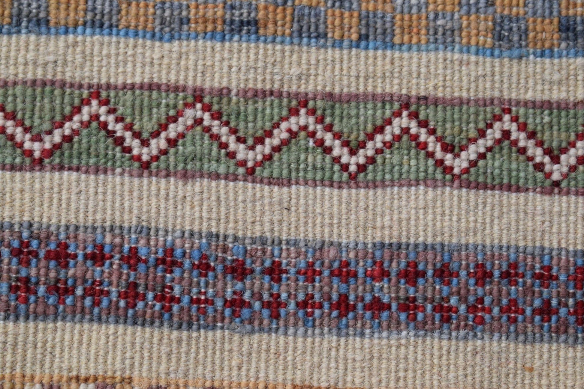 A close-up of an Afghan Yekta runner featuring horizontal bands of geometric patterns in wool.