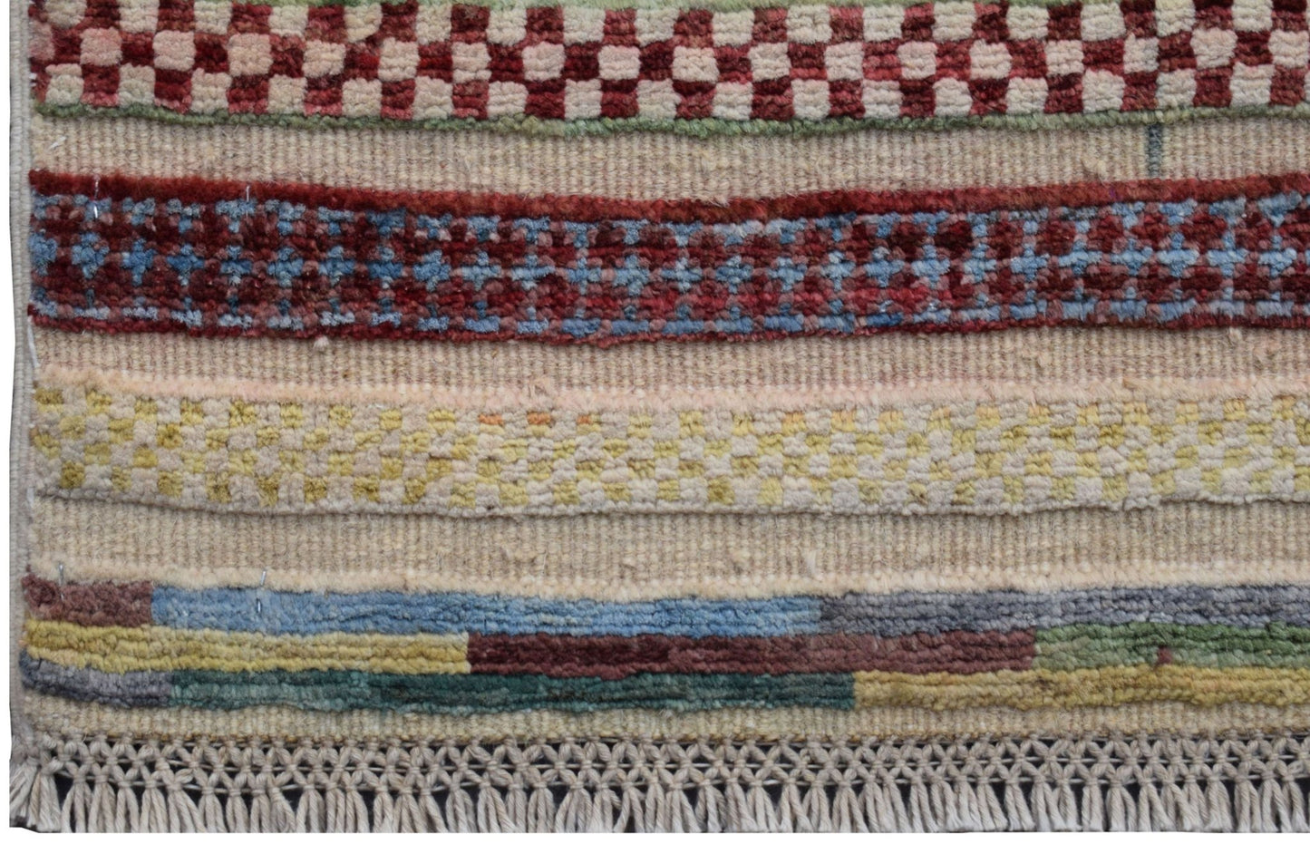 A handmade Afghan Yekta runner featuring horizontal bands of geometric patterns and colorful wool.