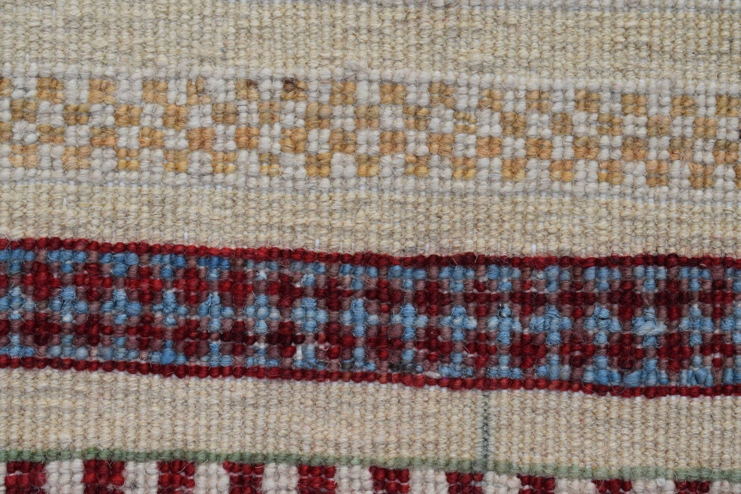 A close-up of an Afghan Yekta runner featuring horizontal bands of cream, gold, and red patterns.