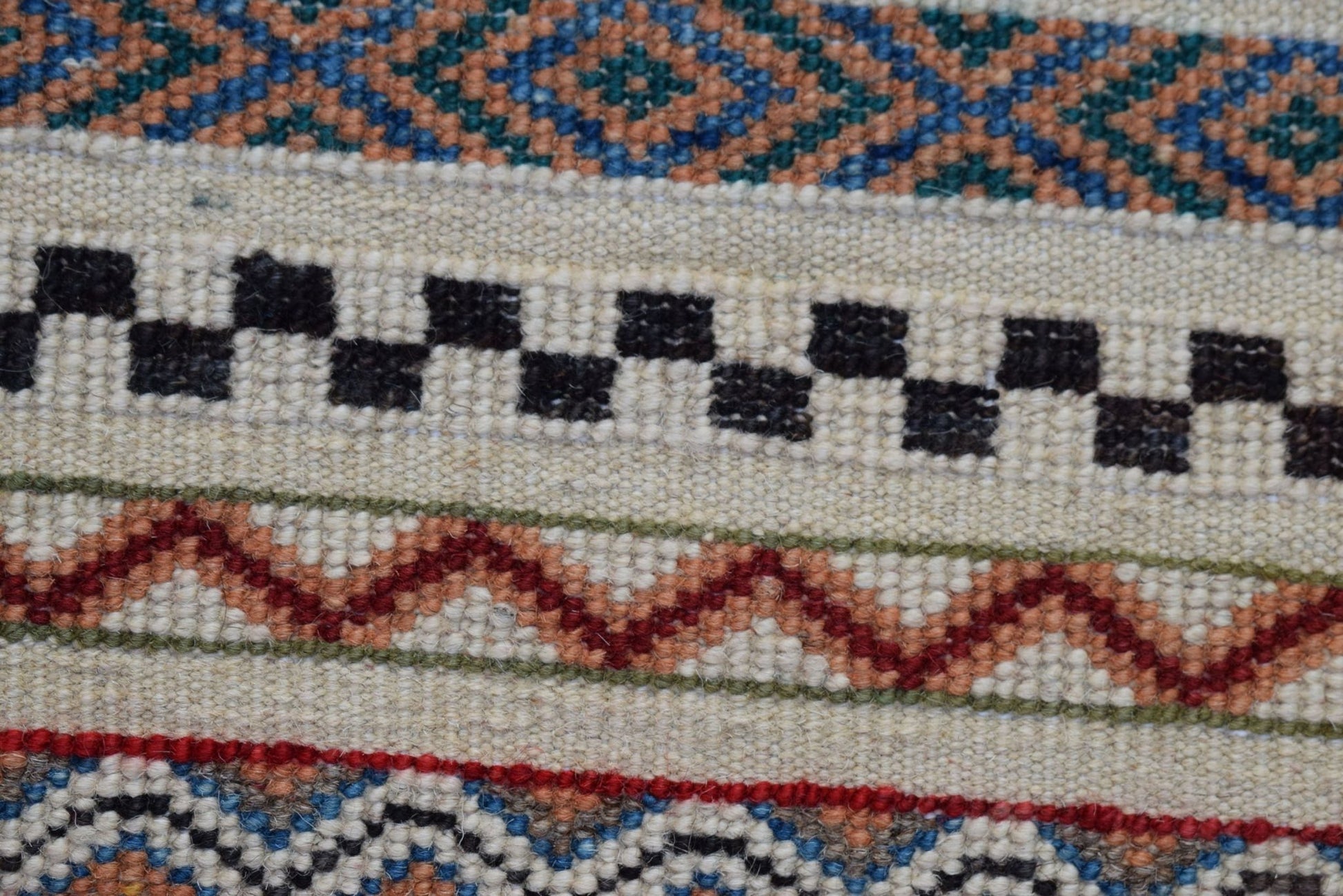 A close-up of an Afghan Yekta runner featuring geometric patterns in blue, orange, and black wool.