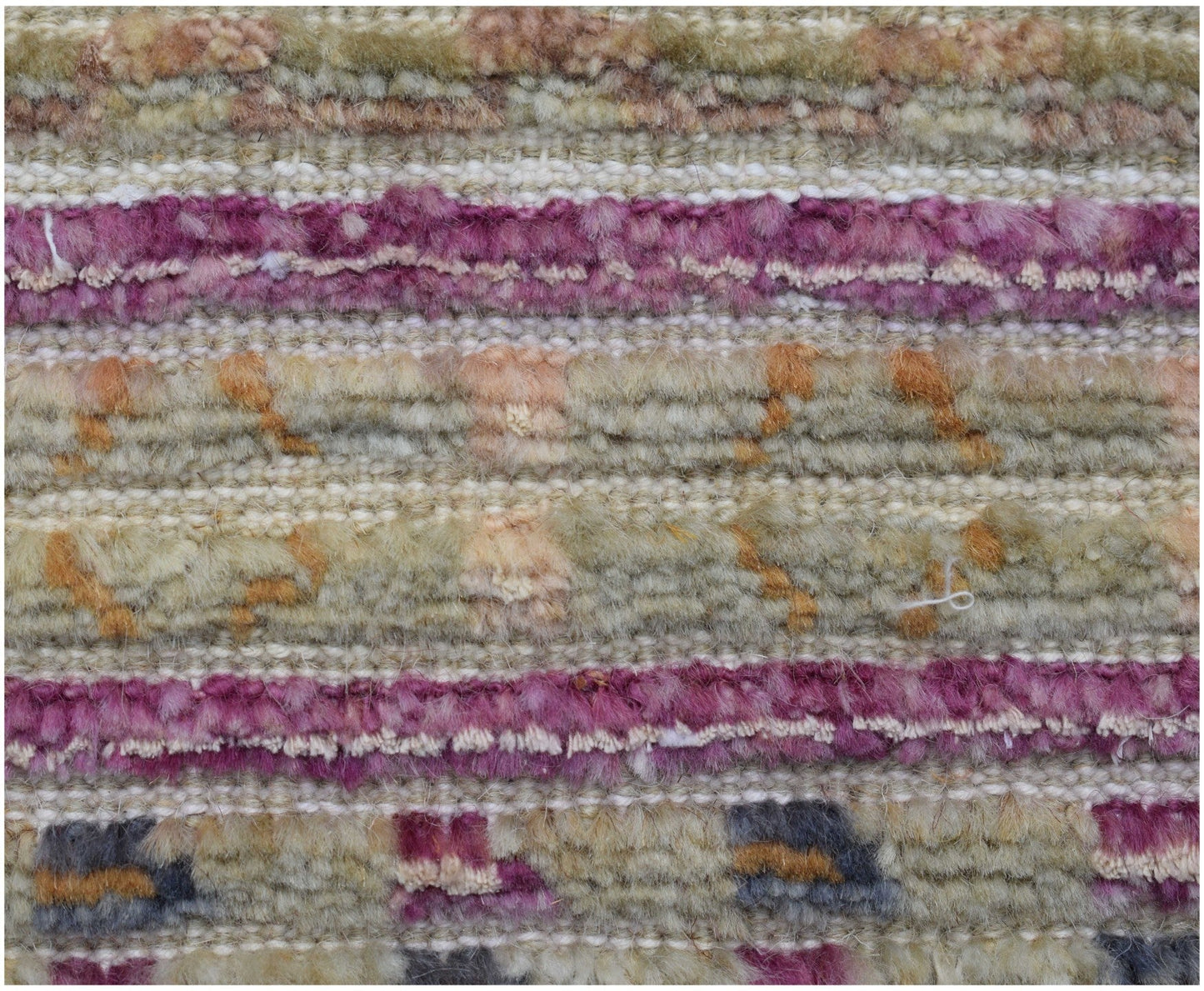A close-up of a handmade Afghan rug featuring horizontal stripes of textured wool in purple and tan.