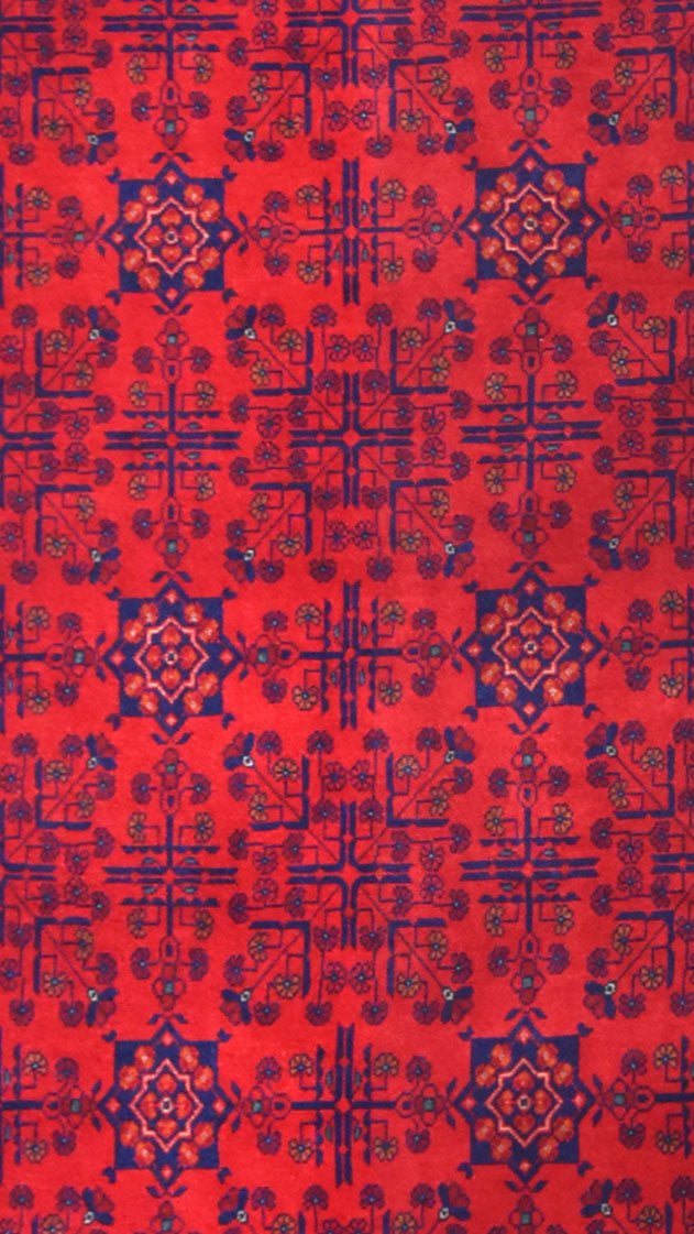 An Afghan Biljik runner featuring a repeating geometric floral pattern in deep red and blue.