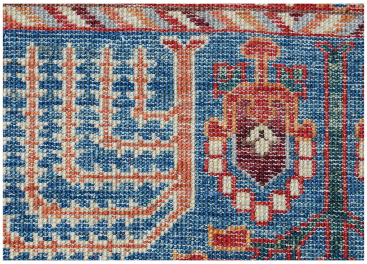 A close-up of an Afghan Chobi runner featuring intricate geometric patterns in blue and red wool.