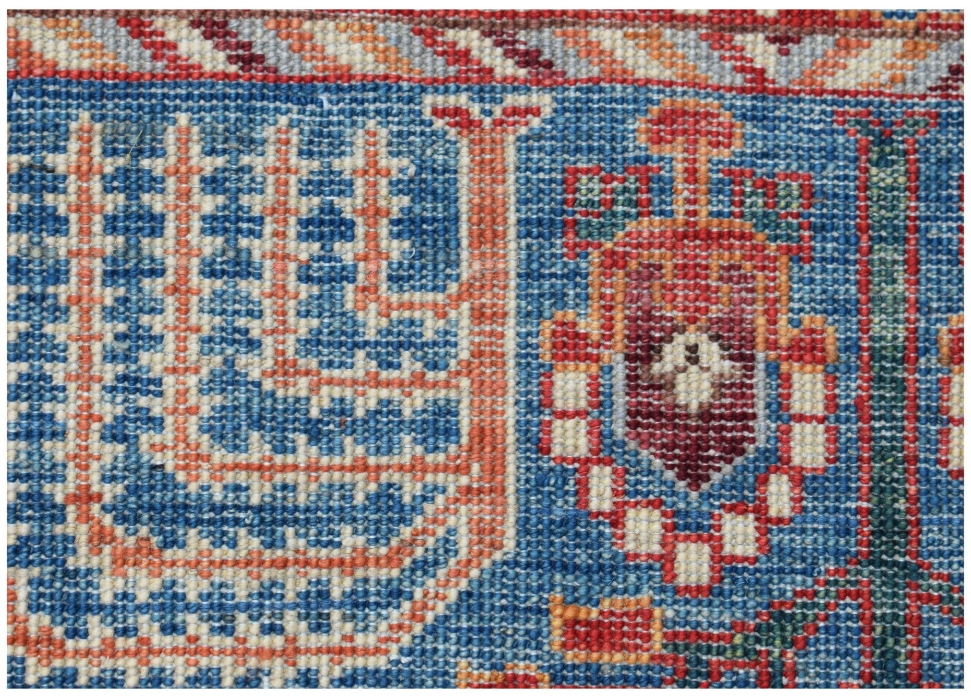A close-up of an Afghan Chobi runner featuring intricate geometric patterns in blue and red wool.