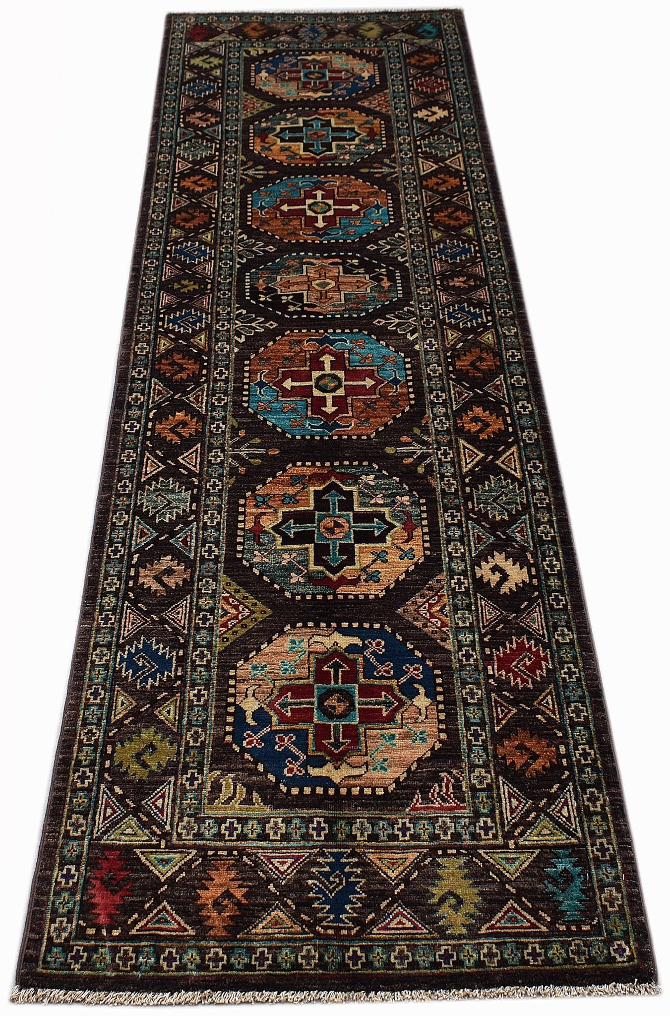 A handmade Afghan Chobi runner rug featuring geometric medallions on a dark brown background.
