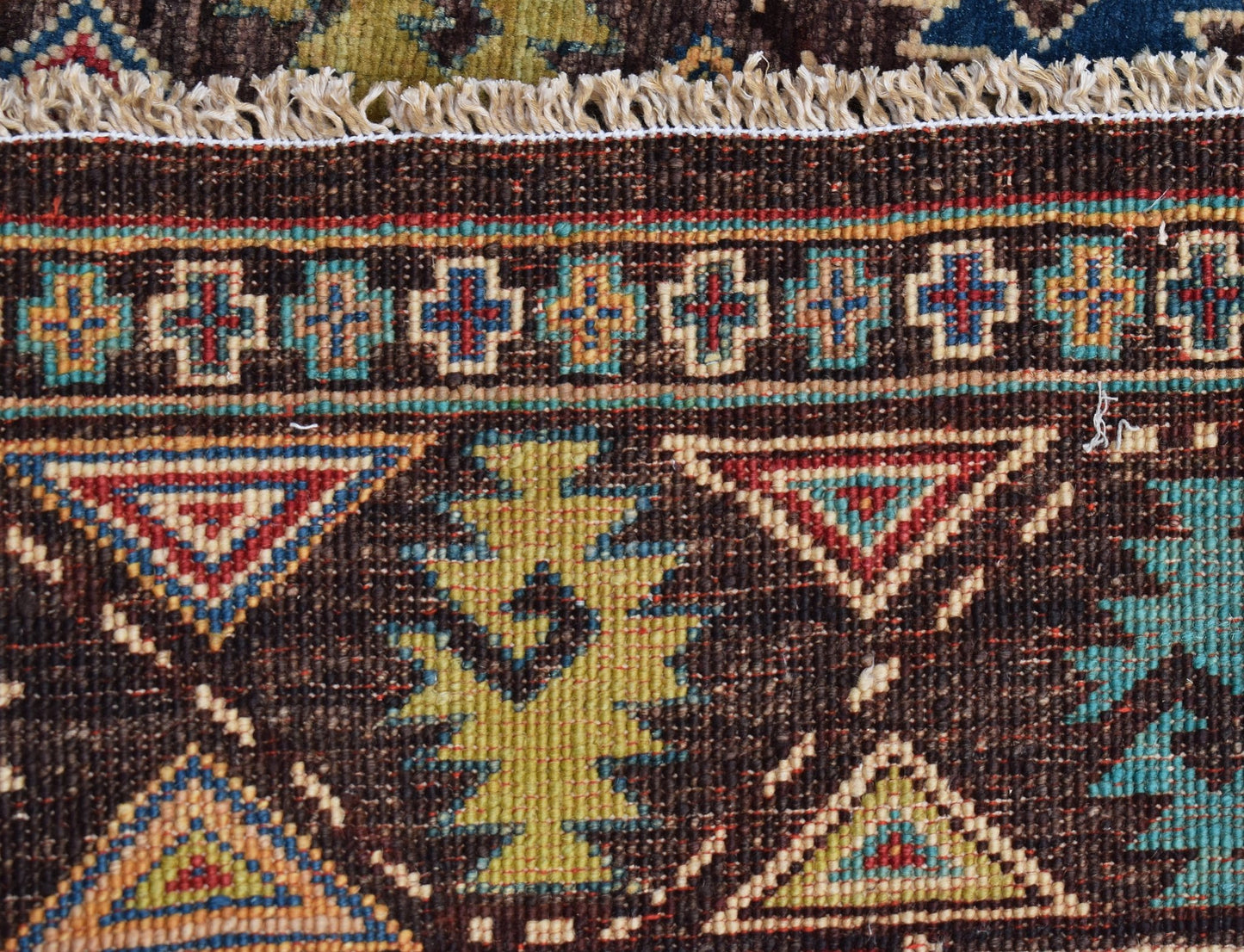 A close-up of a handwoven Afghan Chobi runner featuring geometric patterns in earthy tones.