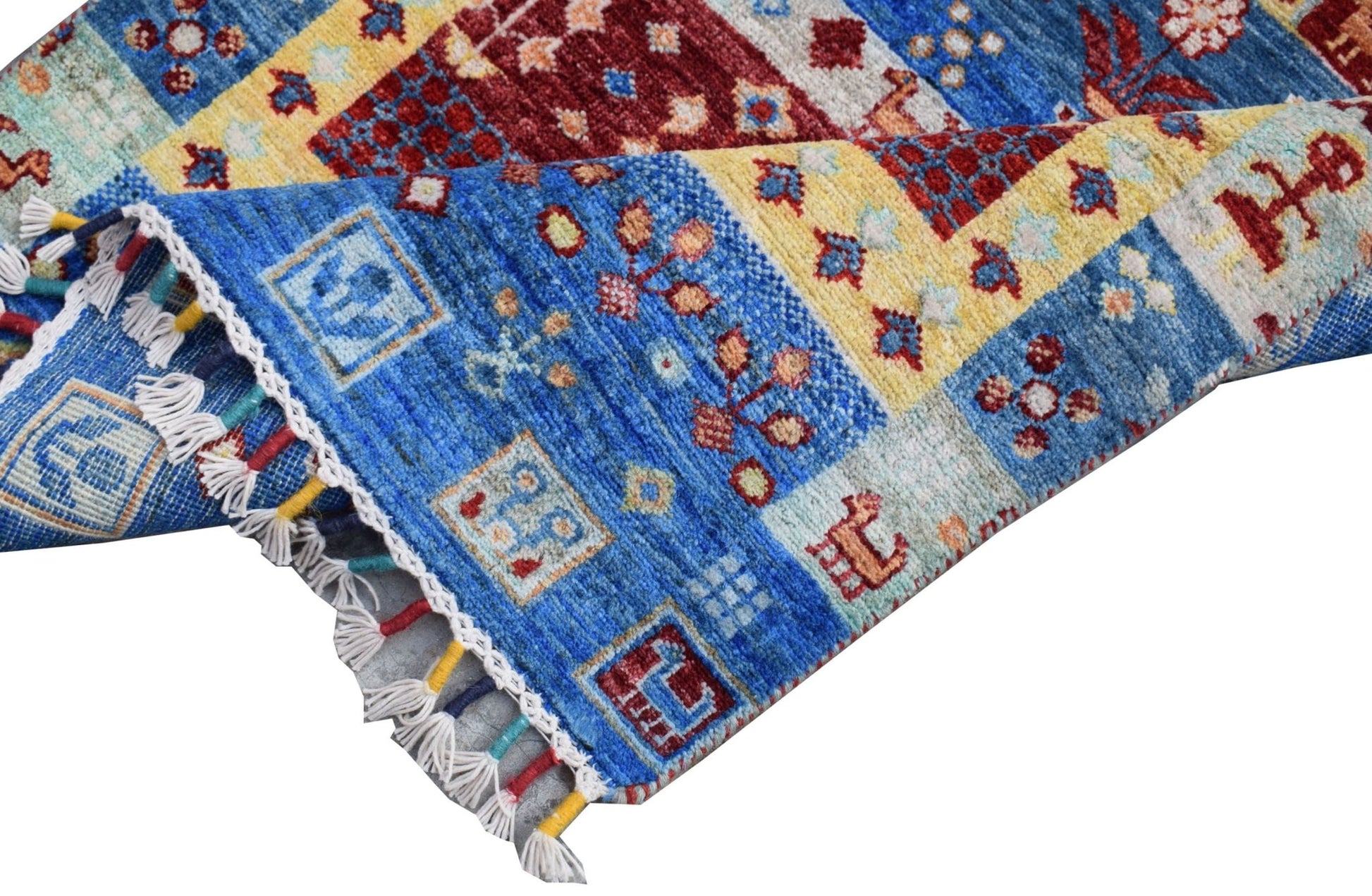 A handmade Afghan Chobi runner featuring a vibrant patchwork of blue, red, and yellow geometric motifs.