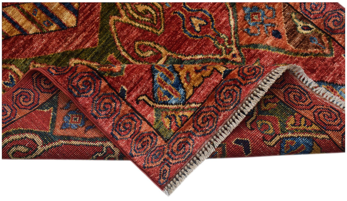 A corner of a handwoven Afghan Chobi runner featuring traditional red, blue, and gold patterns.